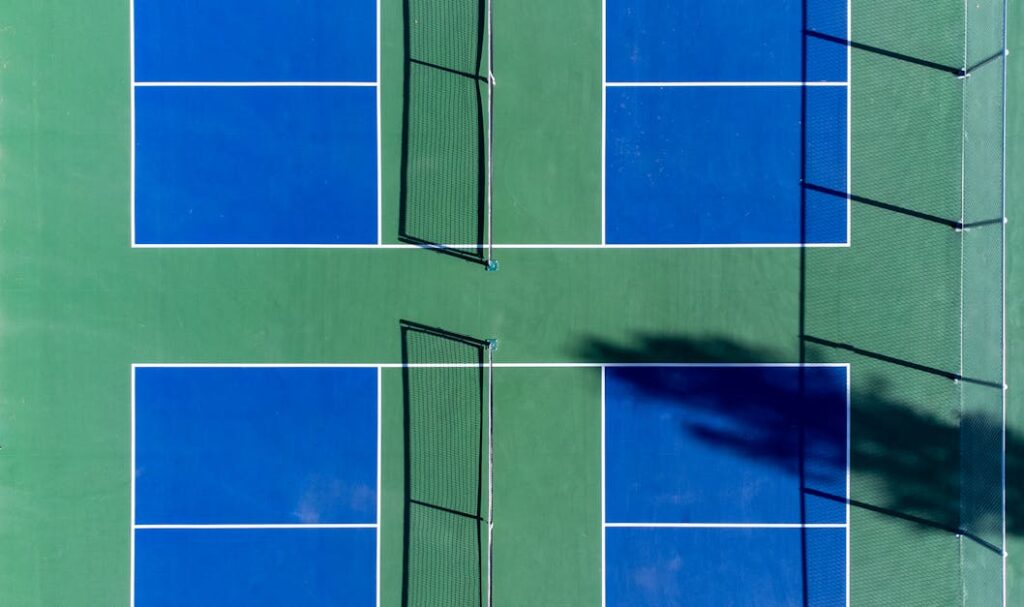 Top-down photo of vibrant blue and green sports courts with nets, perfect for recreational activities.